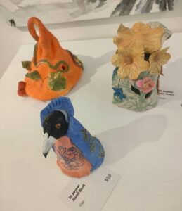Gallery News 75 Three clay figurines including a pumpkin hat, crow and flower vase