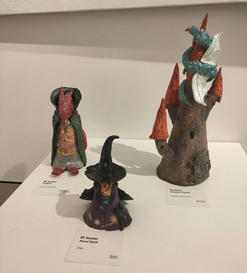 Three clay figurines including a castle, witch and dragon